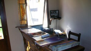 Un bureau en bois, avec des livres, un téléphone et un téléviseur fixé au mur.