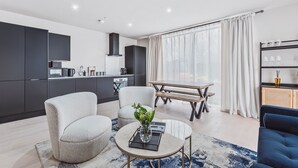 A modern living room with a sofa, a coffee table, and a dining area with a table and chairs. - Stylish new-build FREE parking, 10min to BHX & NEC (Birmingham)