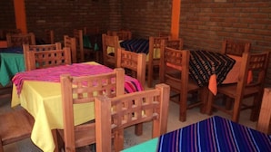A dining area with wooden tables and chairs, each with a colorful tablecloth. - Hotel Rincón Mágico (El Fuerte)