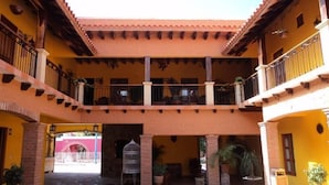 A multi-level courtyard with balconies, potted plants, and a central open space. - Hotel Rincón Mágico (El Fuerte)