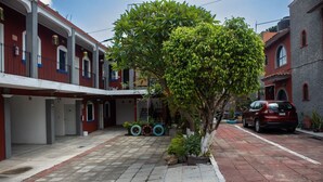 A courtyard with a tree, potted plants, and a parked car. - Hotel casa zoque colonial  (Tuxtla Gutiérrez)
