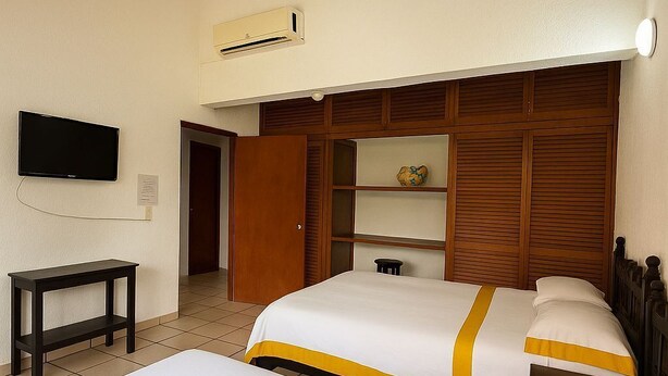 A hotel room with two beds, a TV, a desk, and a wardrobe. - Hotel casa zoque colonial  (Tuxtla Gutiérrez)