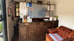 A hotel reception area with a wooden counter, a ceiling fan, and a sofa with a patterned cushion. - Hotel casa zoque colonial  (Tuxtla Gutiérrez)