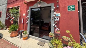 A red building with a reception area, potted plants, and a bell. - Hotel casa zoque colonial  (Tuxtla Gutiérrez)