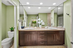 A bathroom with two sinks, a toilet, and a mirror.