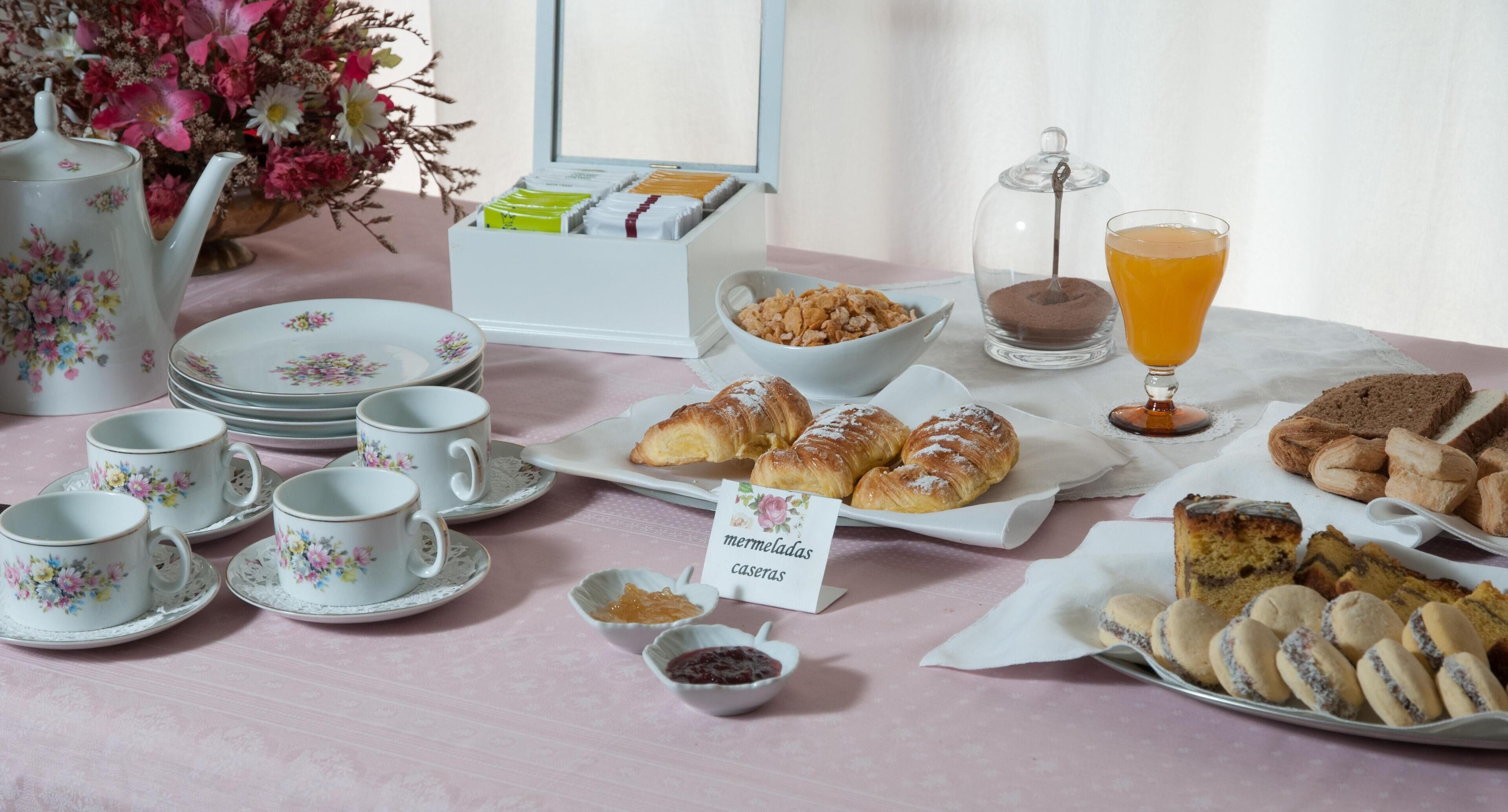 Een ontbijttafel met bloemenbekers, gebak en een theeservies.