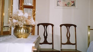 Een eetruimte met een tafel gedekt voor twee personen, een bloevas en een spiegel boven de tafel.