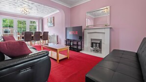 A living room with a fireplace, a TV, and a red carpet.