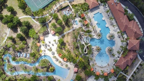 An aerial view of a resort with multiple swimming pools, palm trees, and lounge areas. - 12BR Solterra Mansion + Arcade Game Room & Pool (Davenport)