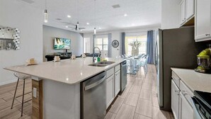 A modern kitchen with a central island, built-in dishwasher, and stainless steel appliances. - 12BR Solterra Mansion + Arcade Game Room & Pool (Davenport)