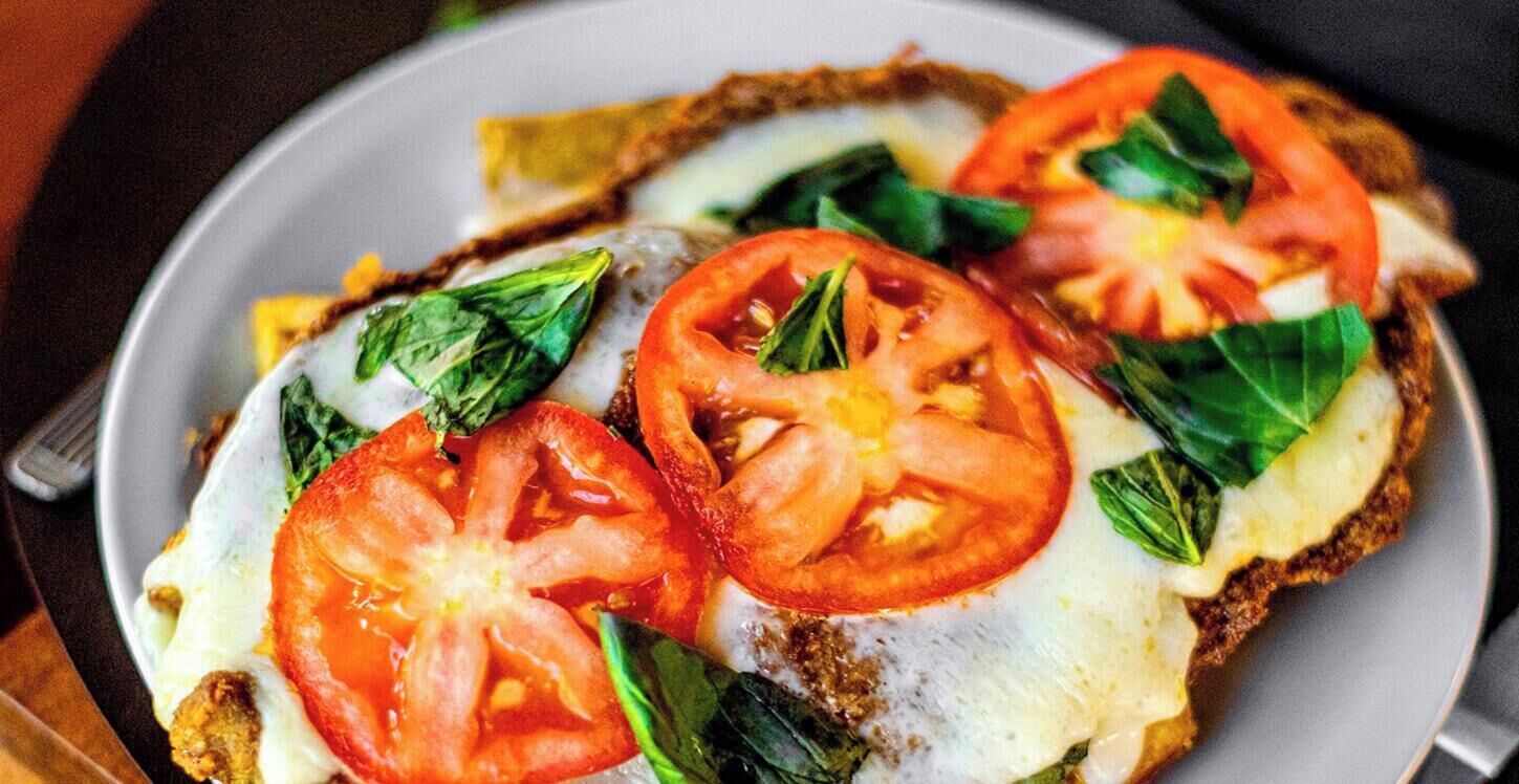 A plate with a sandwich topped with tomato slices and spinach.