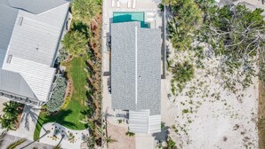 An aerial view of a hotel with a pool, surrounded by palm trees and a well-maintained lawn. - 197 Beach Daze: 3BR Pool Home w/ Deeded Beach Access! (Fort Myers Beach)
