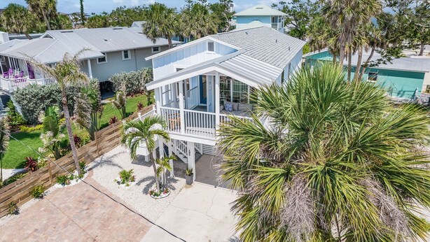 A two-story house with a covered porch, surrounded by palm trees and other vegetation. - 197 Beach Daze: 3BR Pool Home w/ Deeded Beach Access! (Fort Myers Beach)