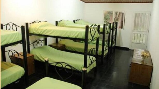 A dormitory room with bunk beds, a wooden cabinet, and a window with curtains. - Paraná Hostel (Parana)