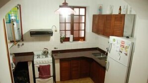 A compact kitchen with a stove, oven, sink, and refrigerator. - Paraná Hostel (Parana)