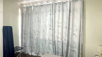 Quarto com cama, varal e cortina estampada com padrão de mármore.