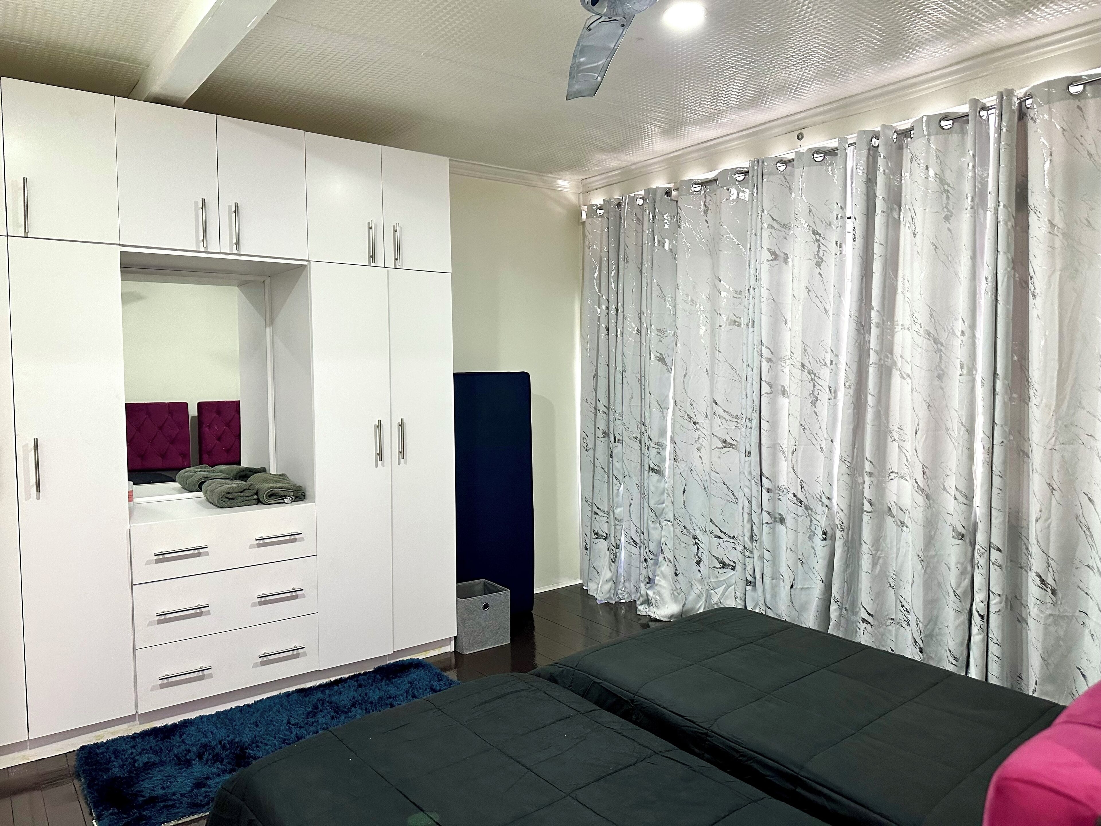 A bedroom with a large wardrobe, a bed, and a window with curtains.