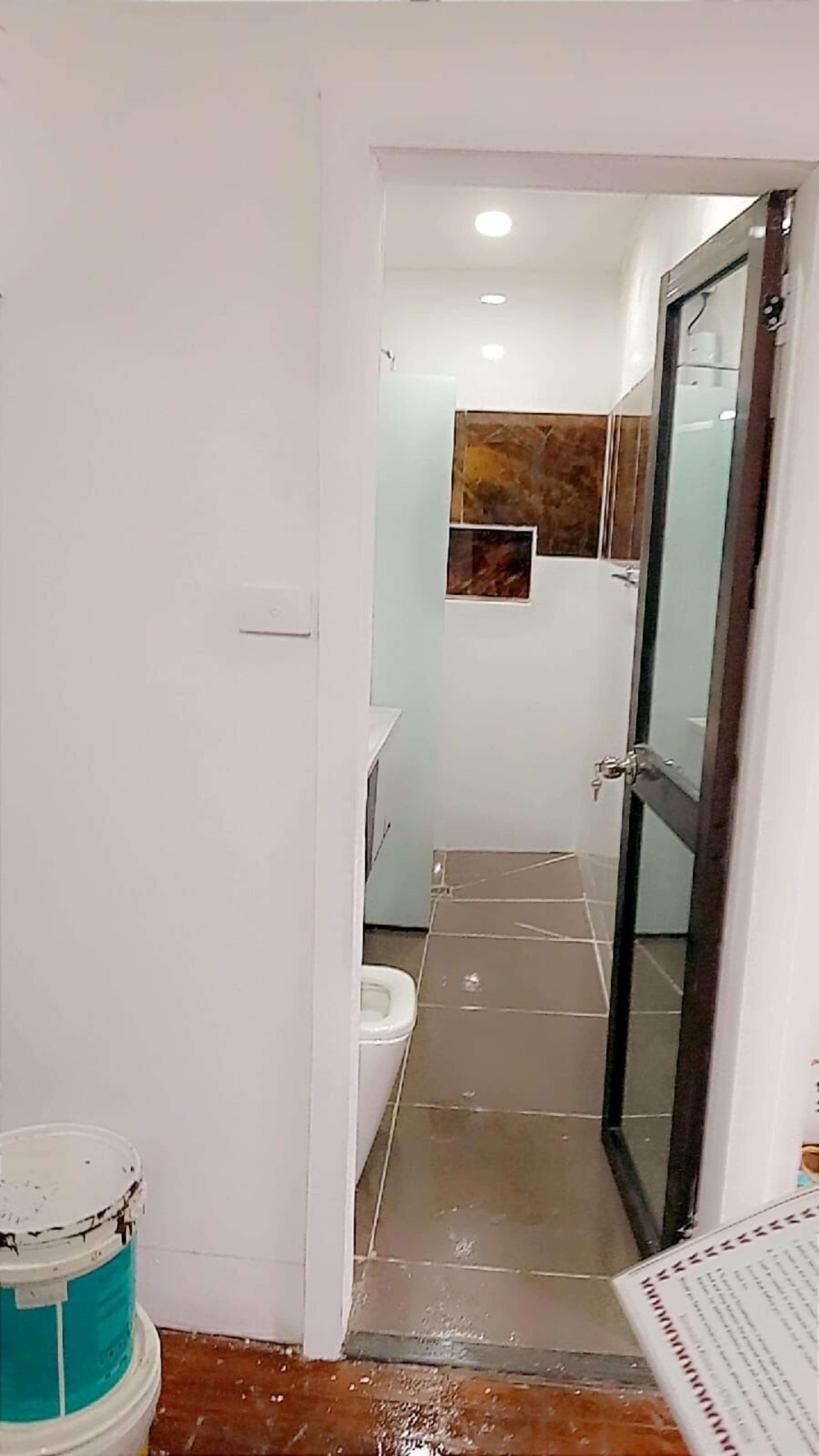 A narrow hallway leading to a bathroom with a toilet, a sink, and a mirror.