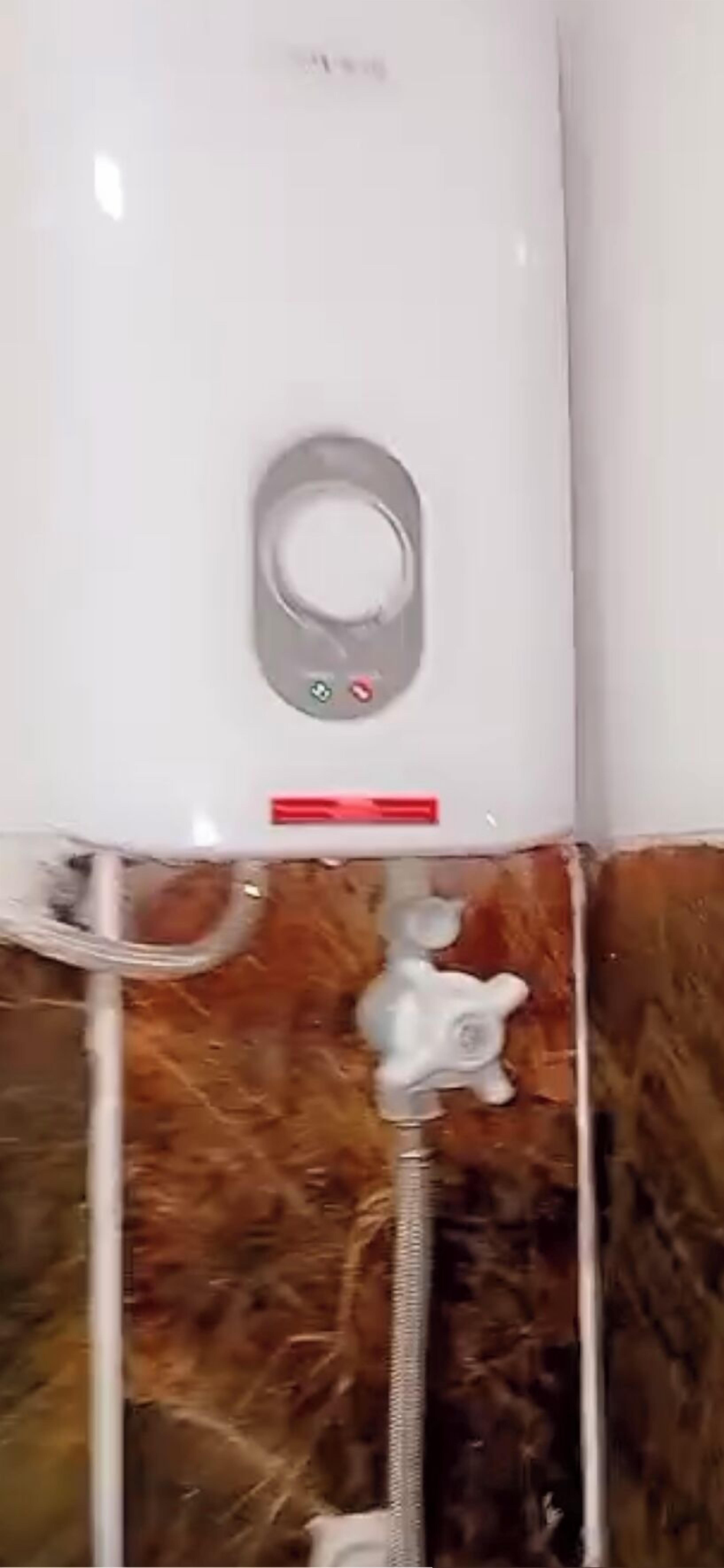 A bathroom with a white shower enclosure, a visible water heater, and a showerhead.