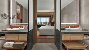 Une chambre d’hôtel moderne dotée de deux vasques, d’un grand lit et offrant une vue sur la ville.