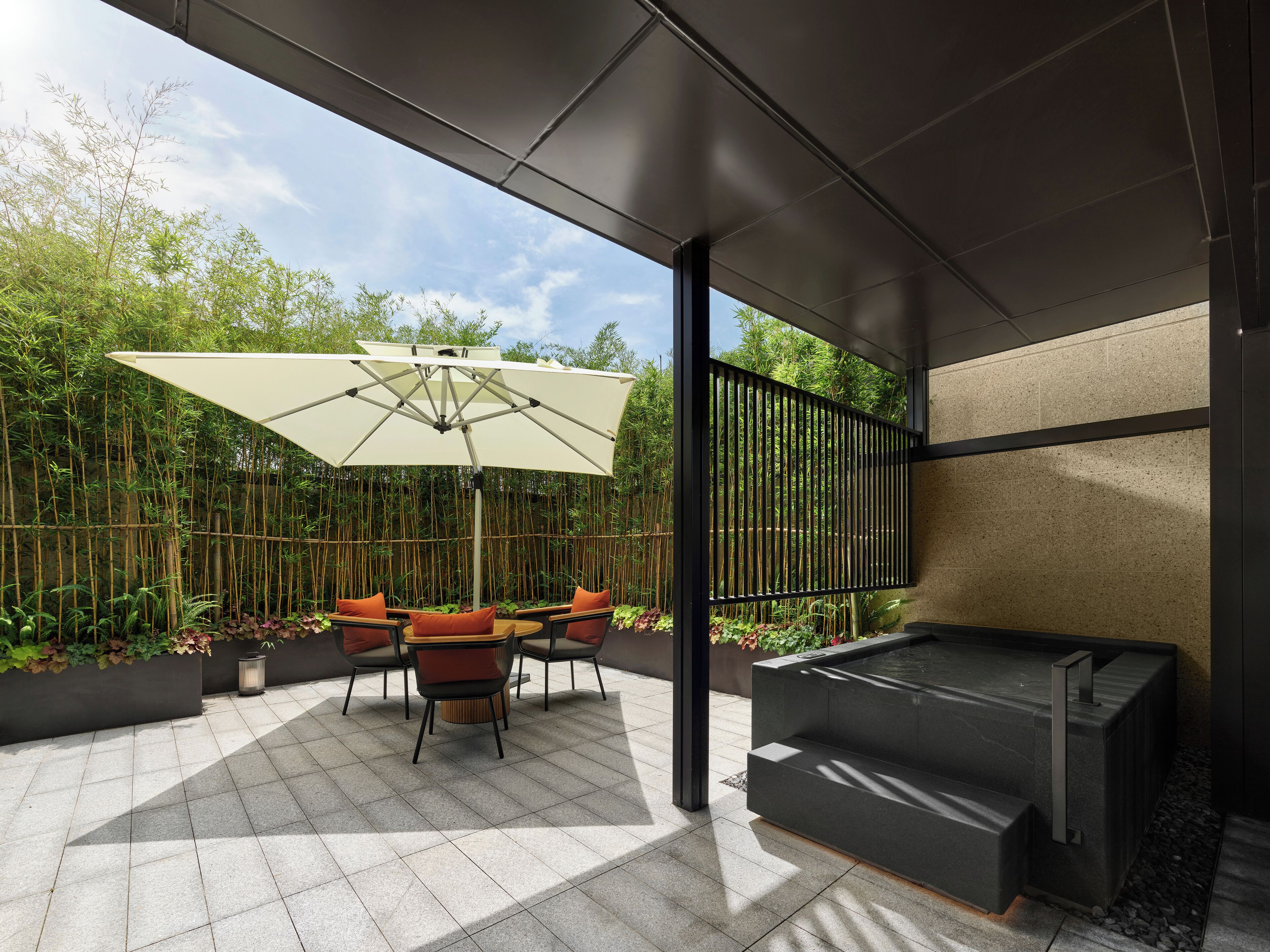 An outdoor patio with a table and chairs, a large umbrella, and a built-in barbecue grill.