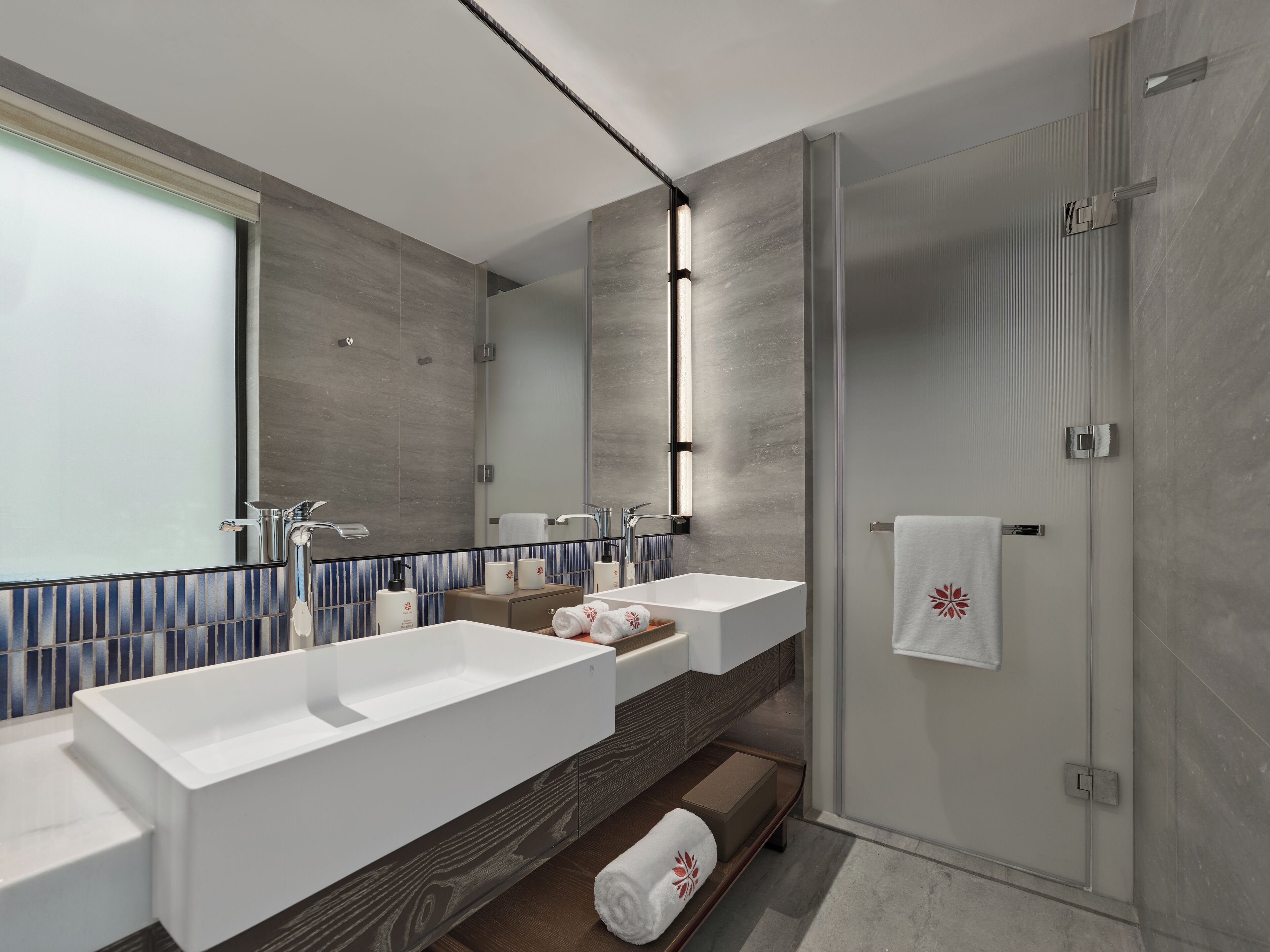 A modern bathroom with two sinks, a large mirror, and a glass shower enclosure.