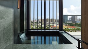 Un intérieur moderne avec une grande fenêtre, un élément décoratif aquatique et une vue sur le paysage urbain.