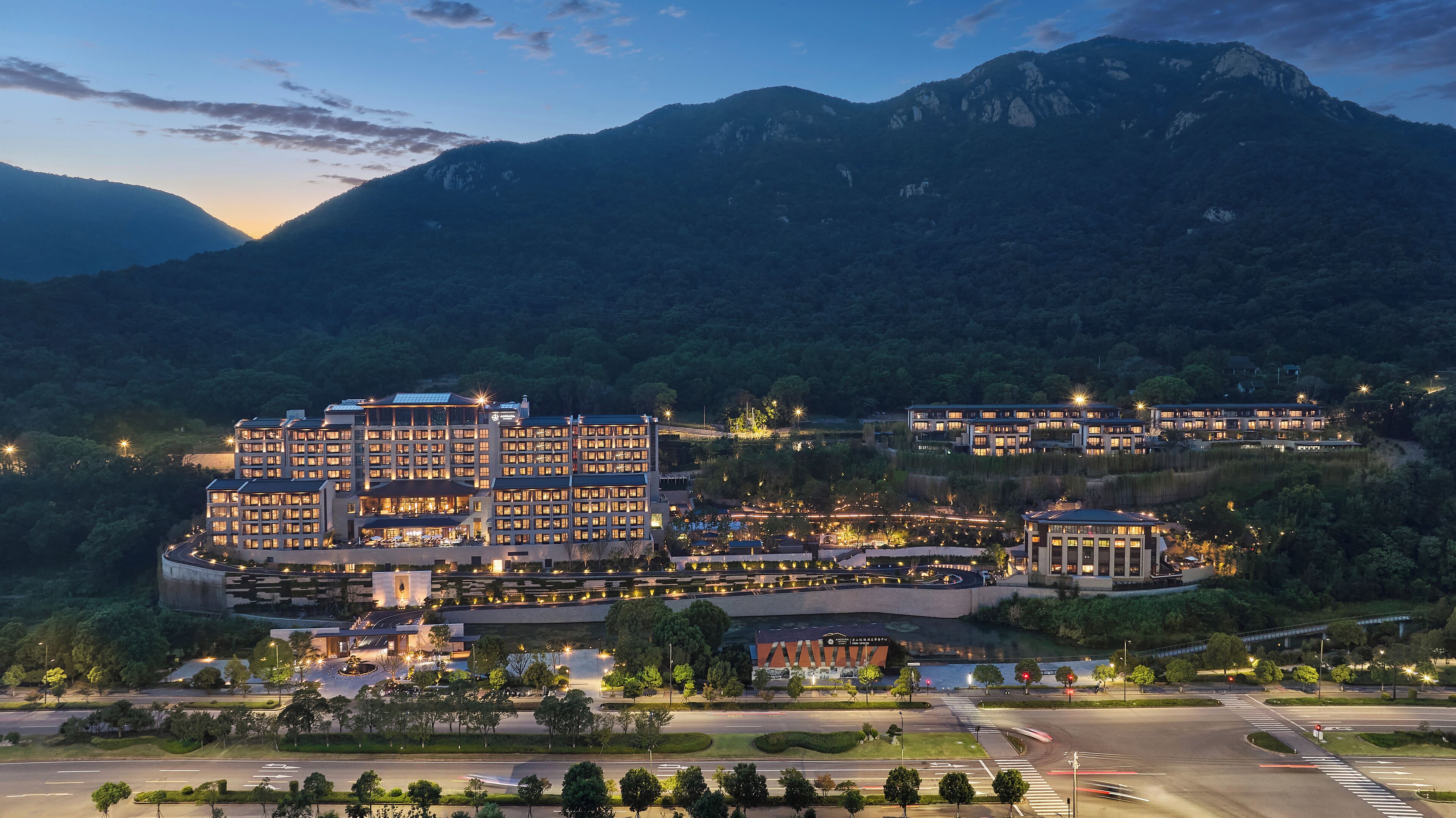 A hotel with multiple buildings, a landscaped area, and a road in the foreground.