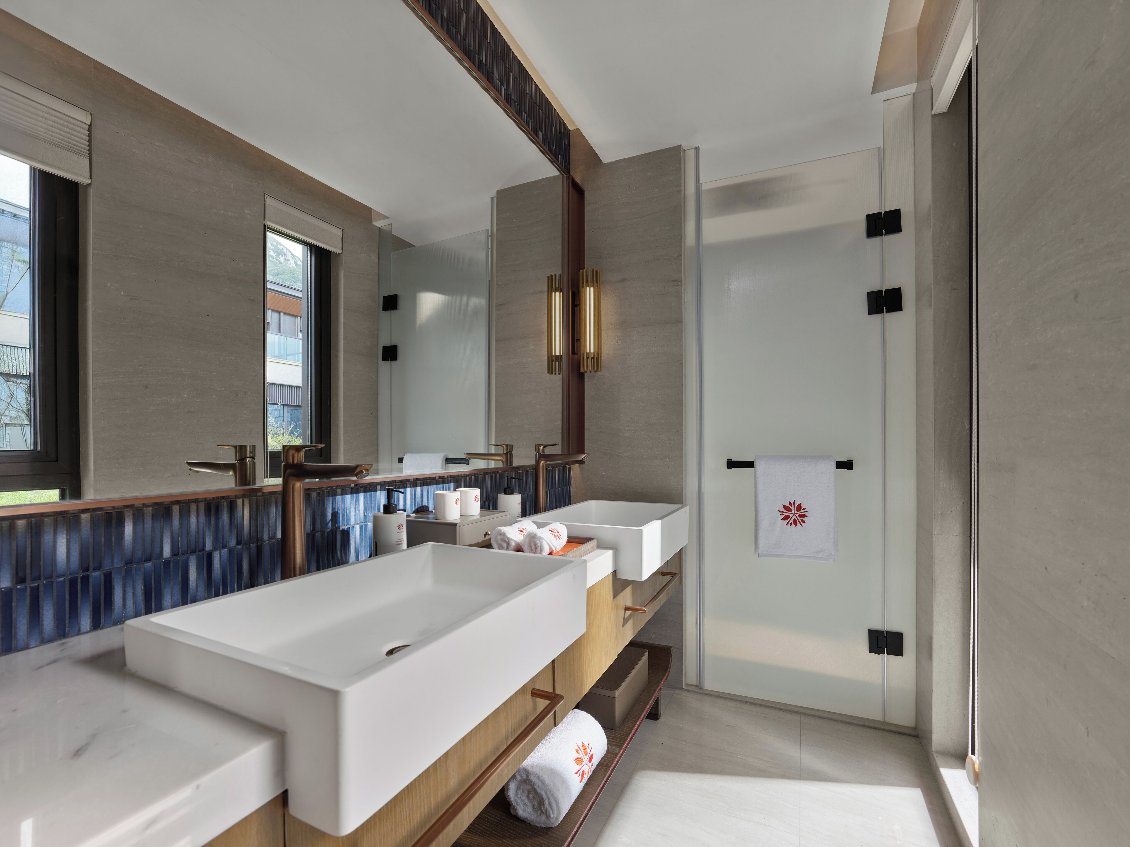 A modern bathroom with a large bathtub, two sinks, and a walk-in shower.