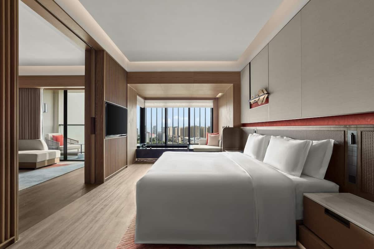 A modern hotel room with a large bed, a television, and a view of the city.