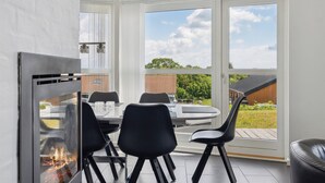 Un espace repas moderne avec une cheminée en verre, une table ronde et des chaises noires.