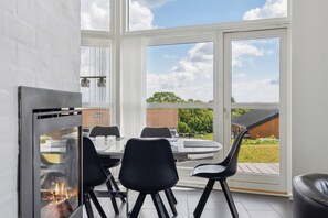 A modern dining area with a glass fireplace, a round table, and black chairs.
