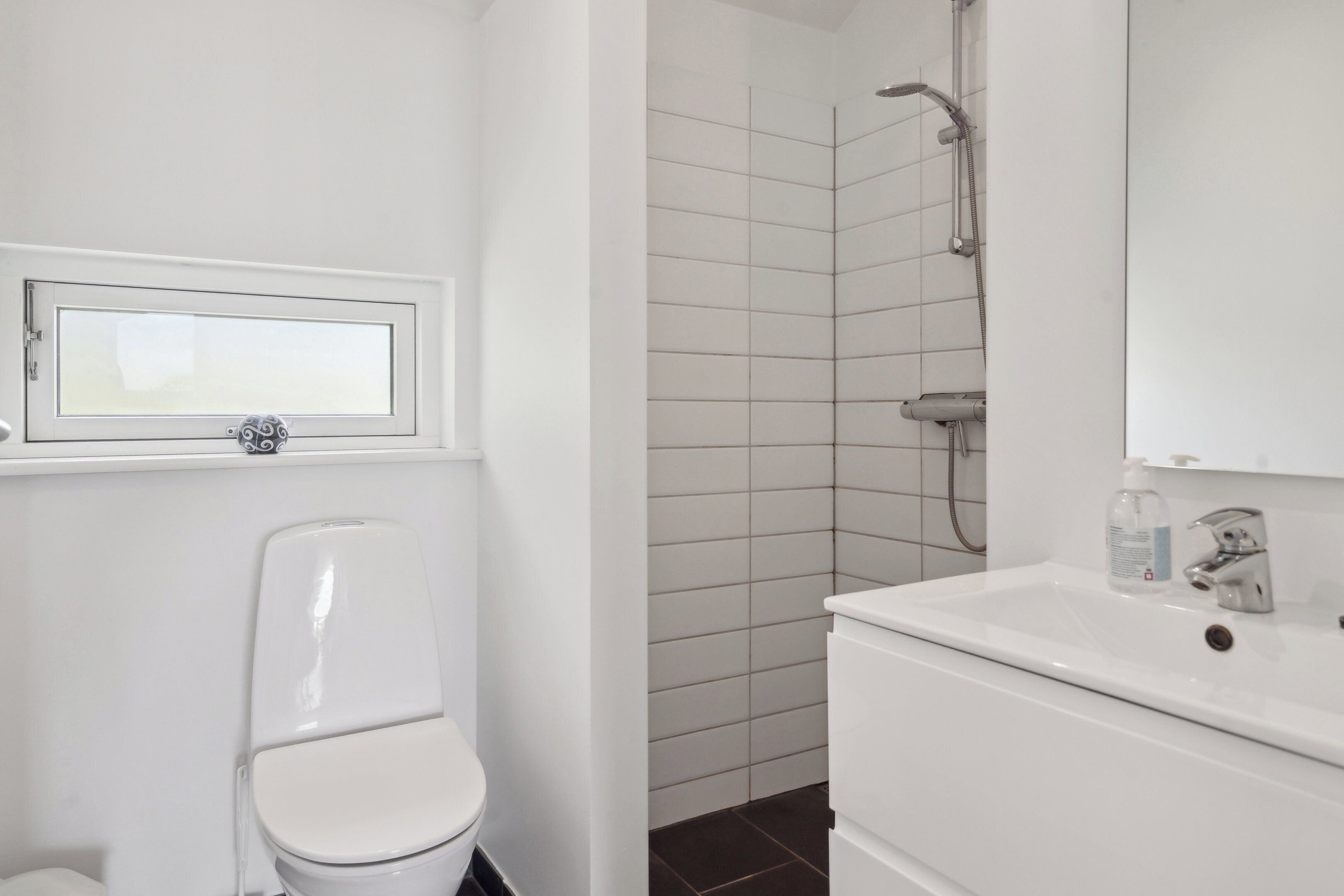 A bathroom with a toilet, a sink, and a shower area.