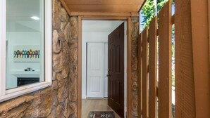 A stone exterior wall, a wooden door, and a 'Home' mat at the entrance. - Stylish Eastside 3BR Family Home Prime Location (Bellevue)