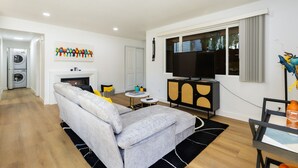 A modern living room with a grey sofa, a flat-screen TV, and a fireplace. - Stylish Eastside 3BR Family Home Prime Location (Bellevue)