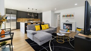A modern living room with a grey sofa, a coffee table, and a fireplace. - Stylish Eastside 3BR Family Home Prime Location (Bellevue)
