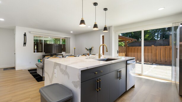 A modern kitchen with a large island, black cabinets, and pendant lighting. - Stylish Eastside 3BR Family Home Prime Location (Bellevue)