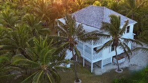 Una casa bianca con tetto in tegole, circondata da palme, situata vicino all'acqua.