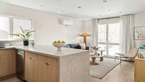 A modern kitchen with a marble countertop, wooden cabinets, and a built-in dishwasher. - Tide House  | Manhattan Beach - Unit A - Seaside w/ Parking (Manhattan Beach)