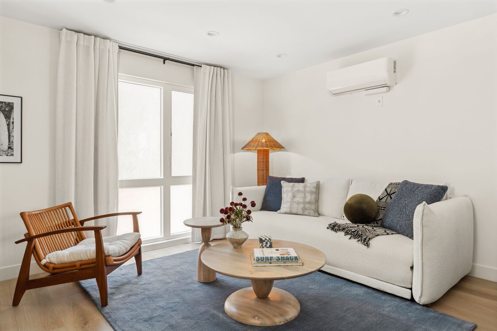 A modern living room with a sofa, a wooden chair, a round coffee table, and a lamp.