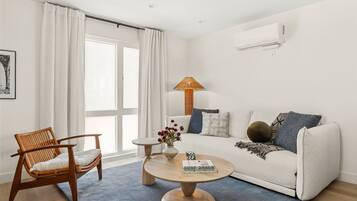 A modern living room with a sofa, a wooden chair, a round coffee table, and a lamp.
