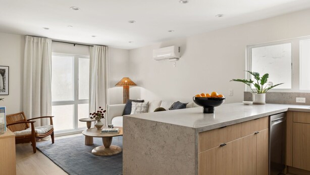 A modern kitchen with a central island, wooden cabinets, and a built-in dishwasher. - Tide House | Manhattan Beach - Unit B - Seaside w/ Parking (Manhattan Beach)