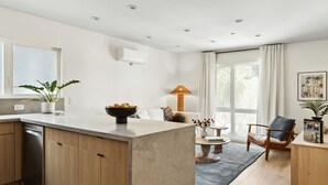 A modern kitchen with a central island, wooden cabinets, and a built-in dishwasher. - Tide House | Manhattan Beach - Unit C - Seaside w/ Parking (Manhattan Beach)