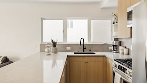 Una cocina moderna con una isla grande, pileta doble y electrodomésticos integrados.