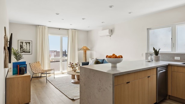 Una cocina moderna con una isla grande, armarios de madera y vistas al exterior.