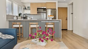 Una cocina moderna con armarios de madera, un refrigerador de acero inoxidable y una barra con dos taburetes.