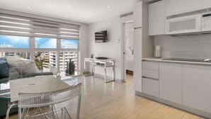 A modern apartment with a living area, kitchenette, and a balcony with city views.