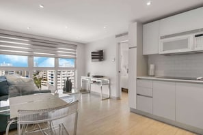 Un apartamento moderno con sala de estar, kitchenette y balcón con vistas a la ciudad.