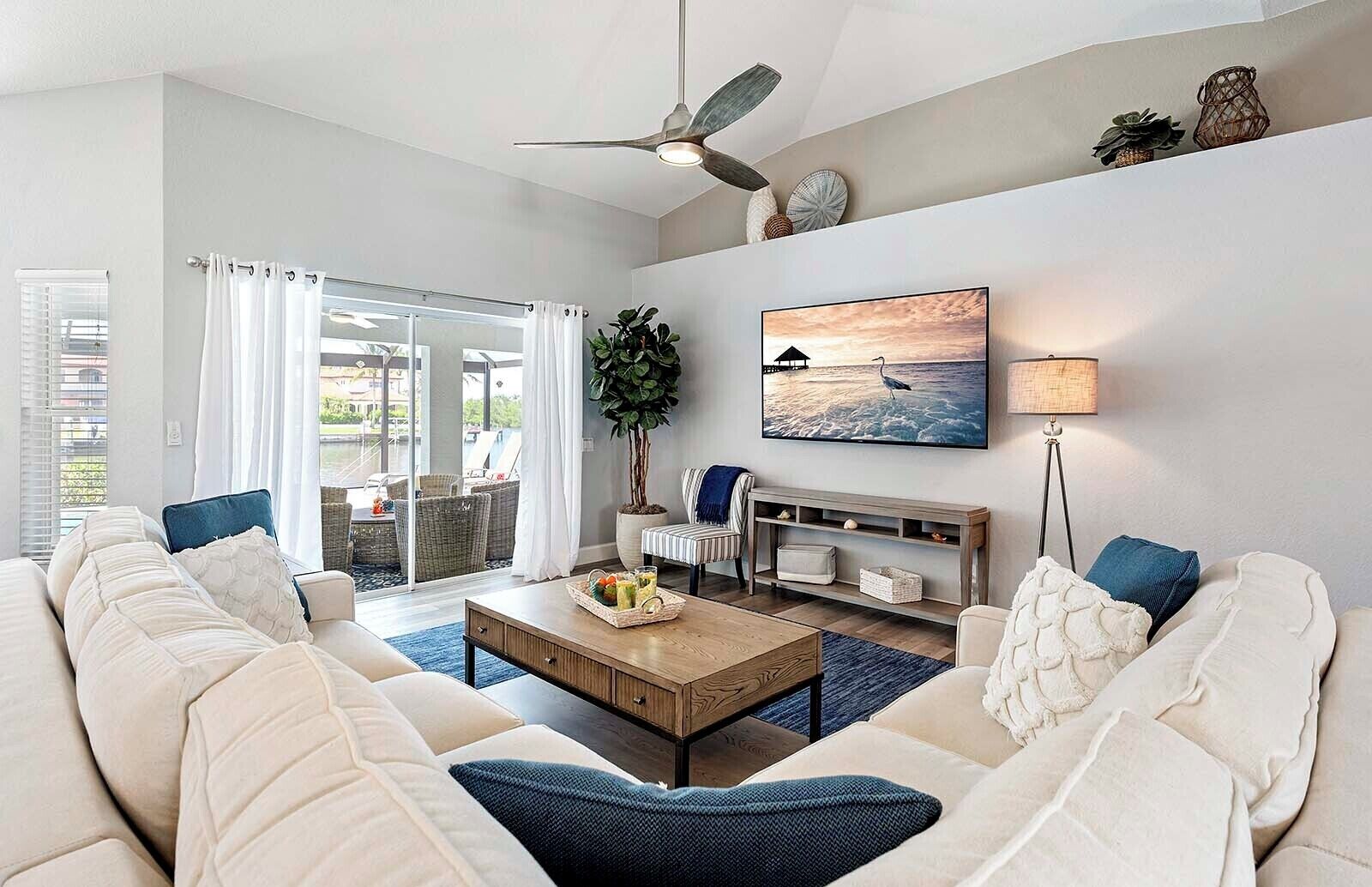 A spacious living room with a large sofa, a coffee table, and a TV. There's a sliding glass door leading to an outdoor area.