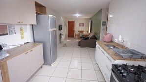 A modern kitchen with a refrigerator, stove, and sink. There is a dining area with a table and chairs.
